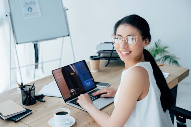 cheerful-latin-businesswoman-using-laptop-with-boo-FA82N8N